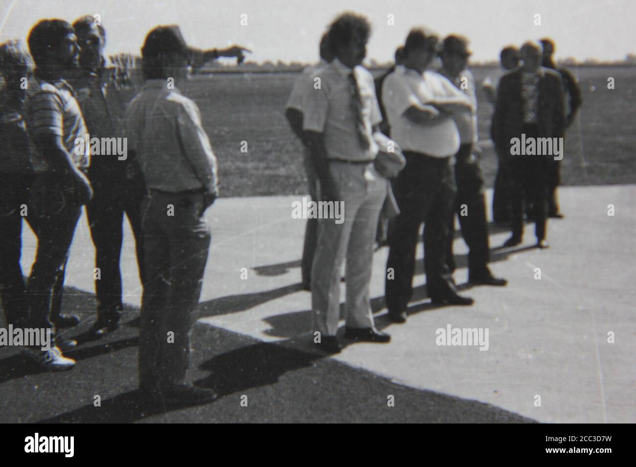 Feine Schwarz-Weiß-Fotografie aus den 1970er Jahren von einem Haufen professioneller Männer, die draußen stehen und eine Demonstration beobachten. Stockfoto