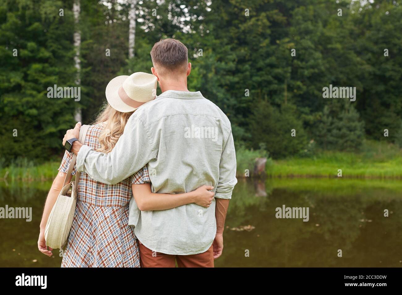Rückansicht Porträt eines romantischen erwachsenen Paar umarmen, während am See in rustikaler Landschaft Landschaft stehen, kopieren Raum Stockfoto
