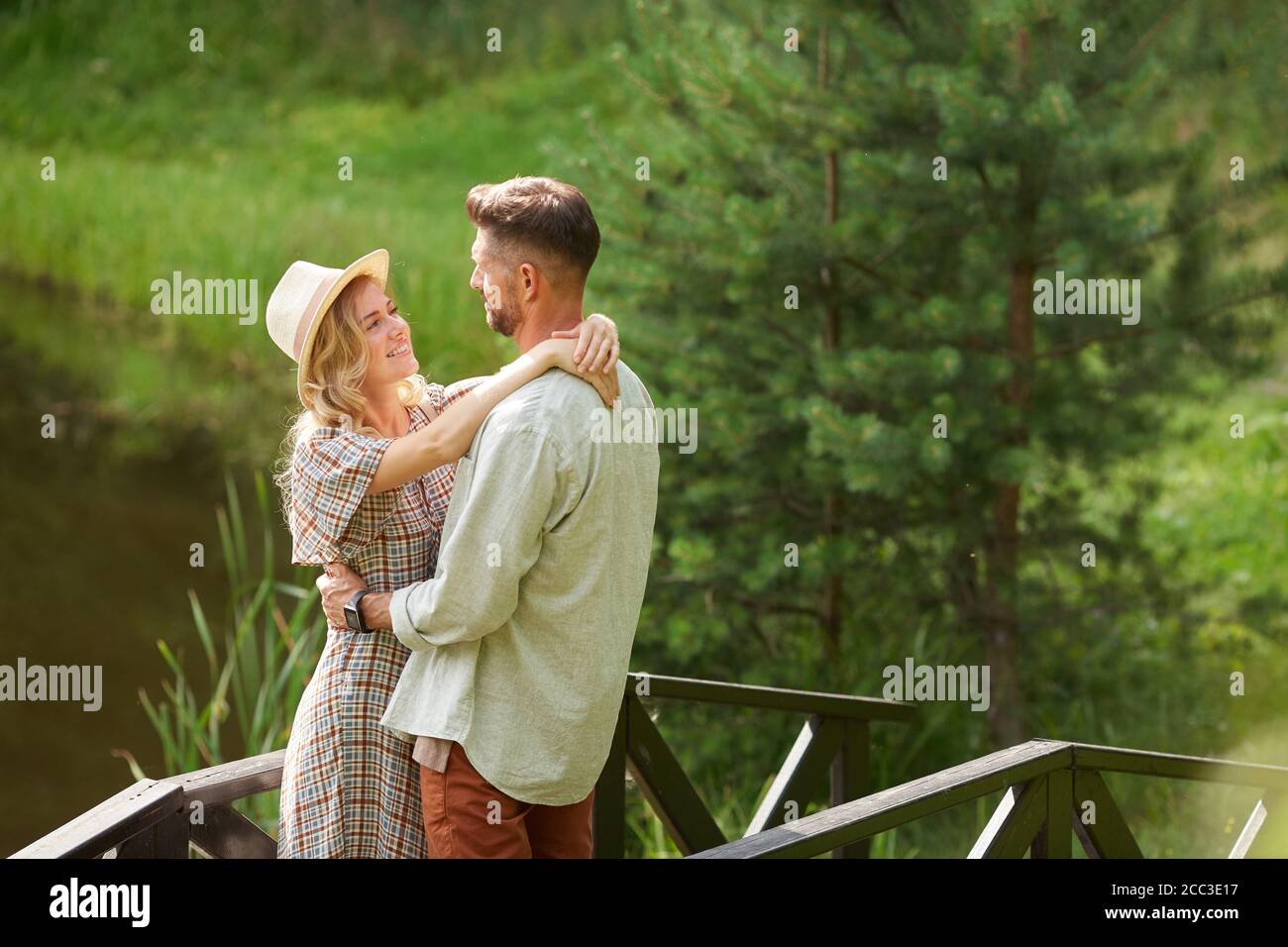 Seitenansicht Porträt von romantischen erwachsenen Paar umarmen und einander beim Stehen am See im Freien in rustikalen Landschaft, kopieren Raum Stockfoto