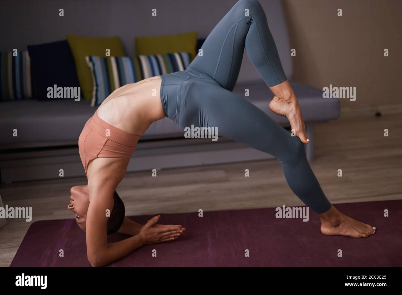 Frau in Leggins und Thema tun Elbow Bridge Übung, Urdhva Dhanurasana Pose. Mädchen, die sich ausarbeitet. Raumhintergrund Stockfoto