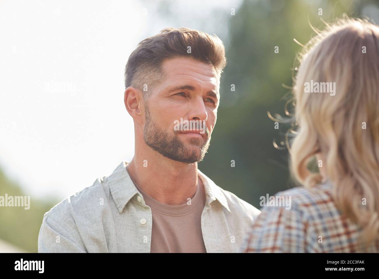 Kopf und Schultern Porträt von schönen erwachsenen Mann Blick auf Freundin, während genießen romantische Datum im Freien in Sonnenlicht, kopieren Raum Stockfoto