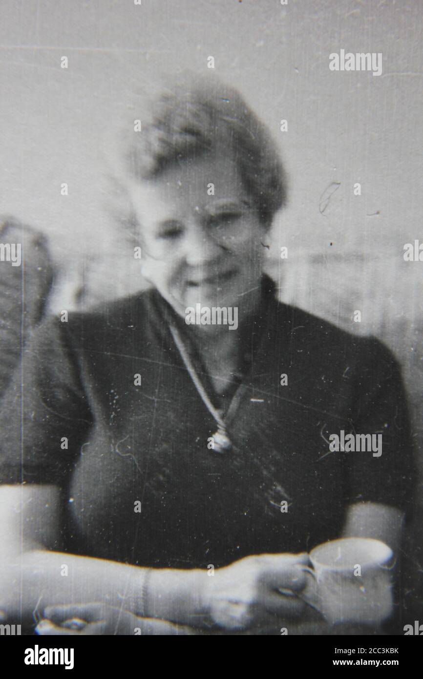 Feine Schwarz-Weiß-Vintage-Fotografie einer älteren Frau aus den 1970er Jahren, die an der Kamera lächelt. Stockfoto