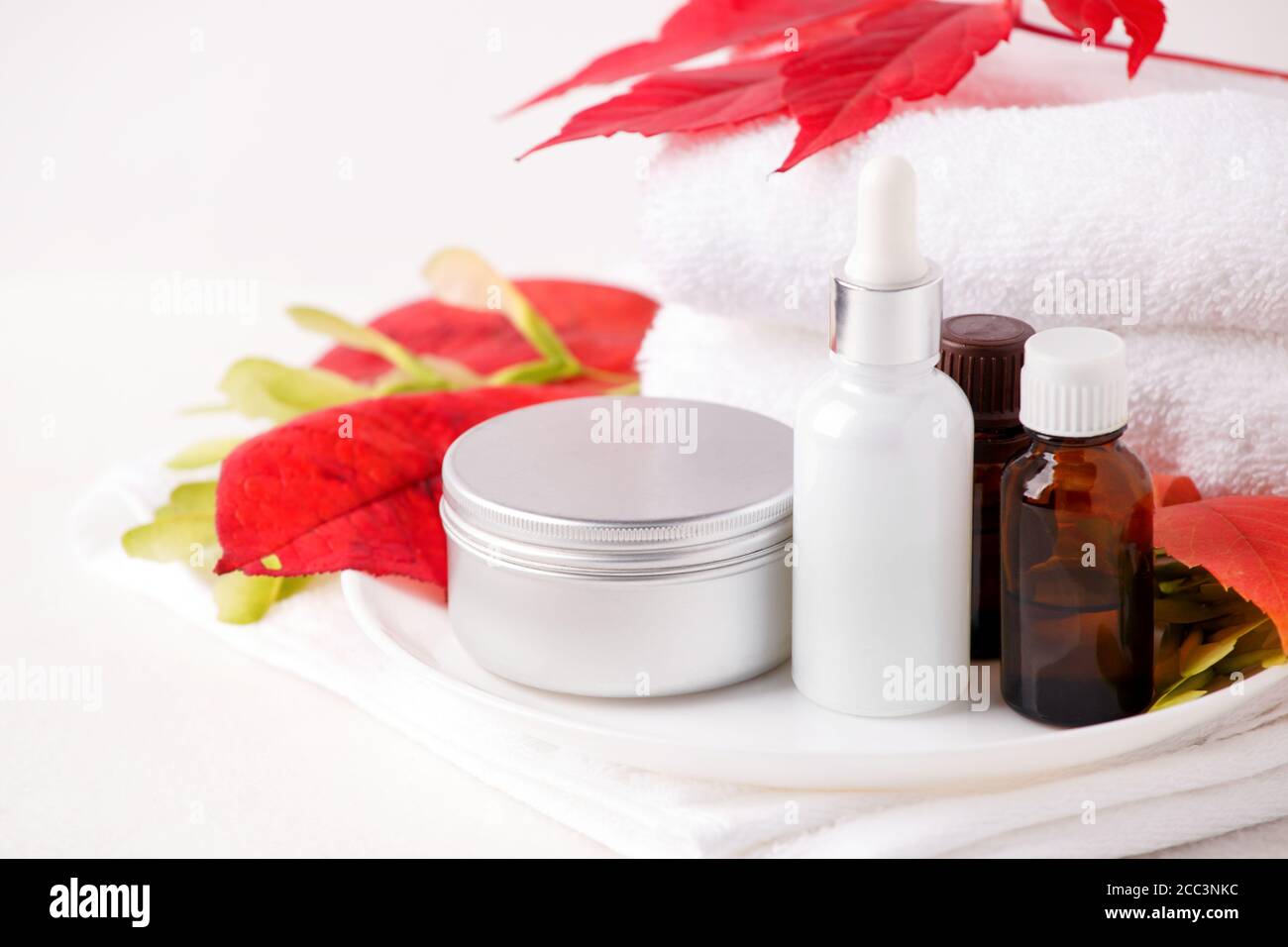 Zero Waste Glas kosmetischen Flaschen und Metall-Glas, Creme, Serum, Seife, Öl auf weißem Tisch. Herbst leuchtend rote Blätter, natürliches Bio-Beauty-Produkt. Spa Stockfoto