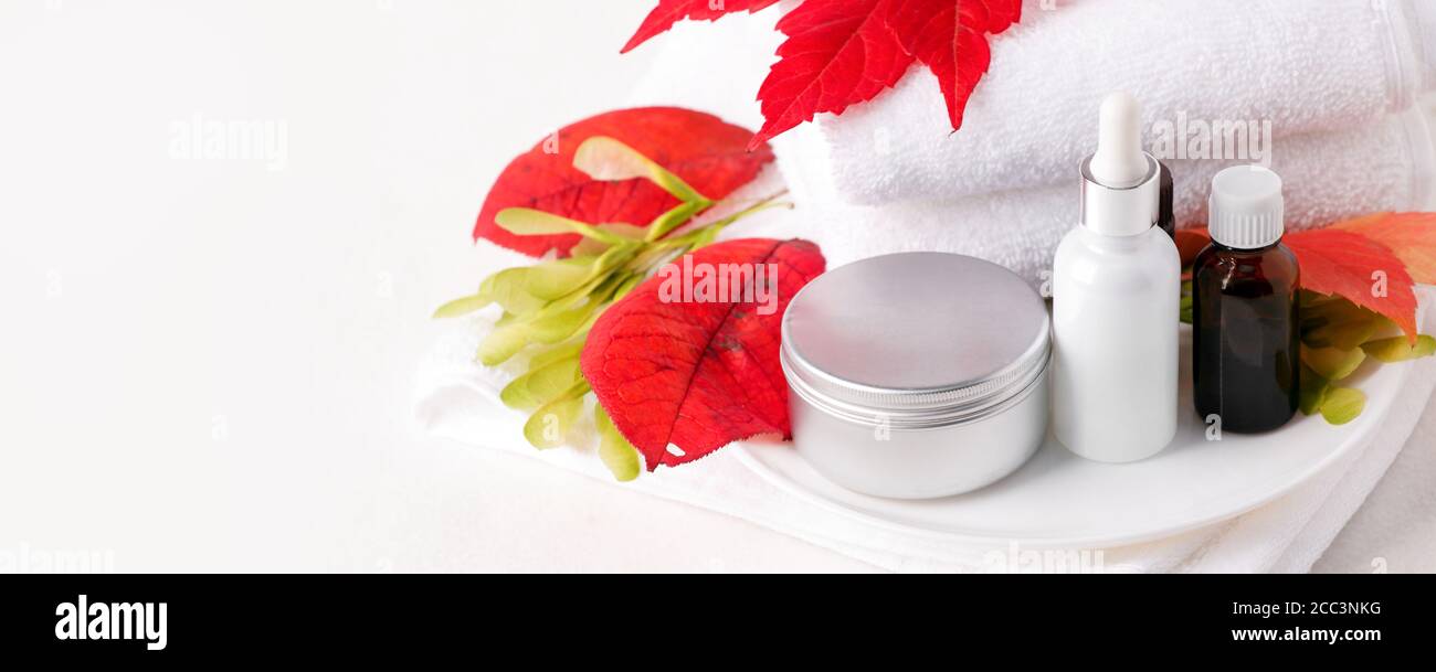 Zero Waste Glas kosmetischen Flaschen und Metall-Glas, Creme, Serum, Seife, Öl auf weißem Tisch. Herbst leuchtend rote Blätter, natürliches Bio-Beauty-Produkt. Spa Stockfoto