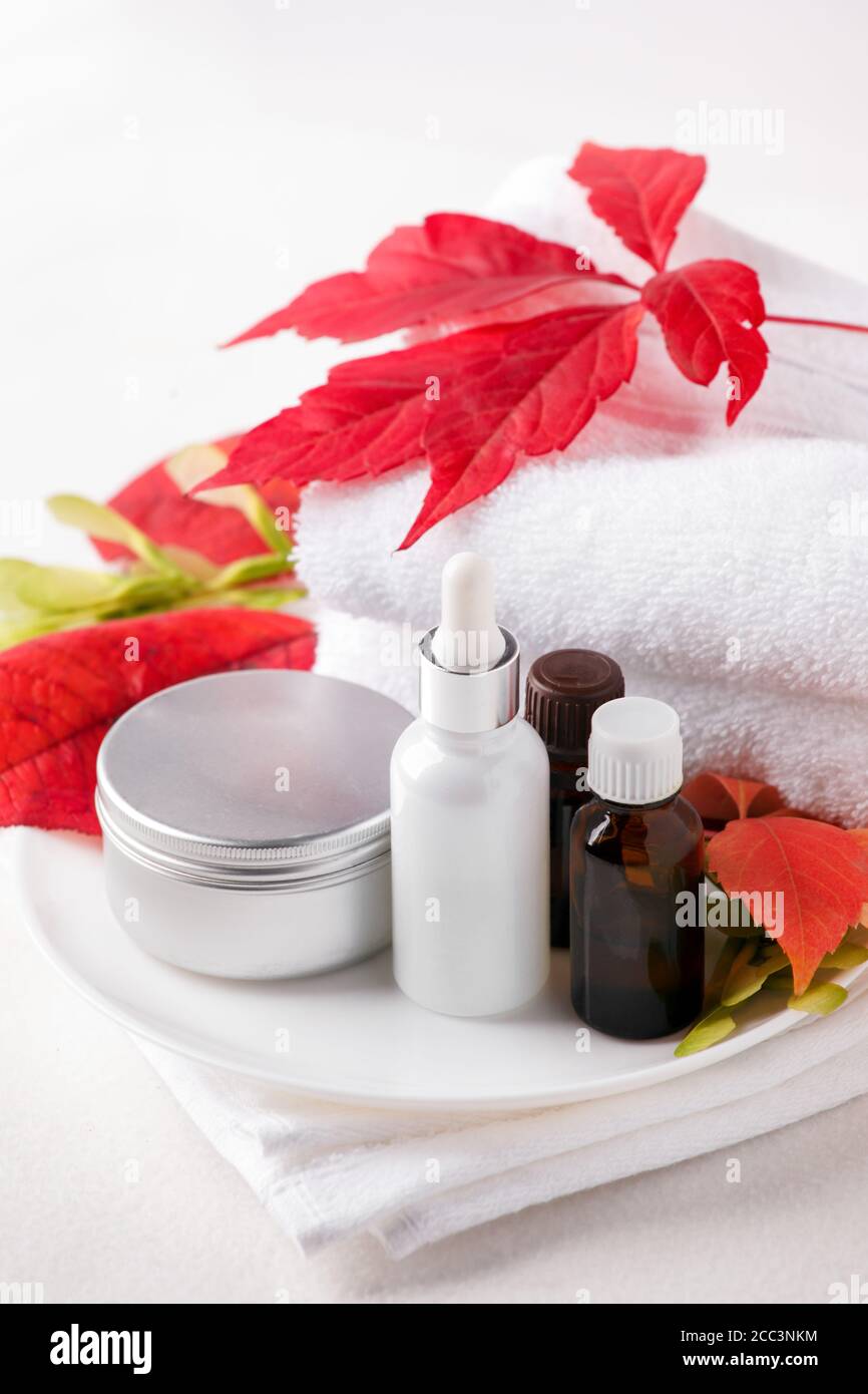 Zero Waste Glas kosmetischen Flaschen und Metall-Glas, Creme, Serum, Seife, Öl auf weißem Tisch. Herbst leuchtend rote Blätter, natürliches Bio-Beauty-Produkt. Spa Stockfoto
