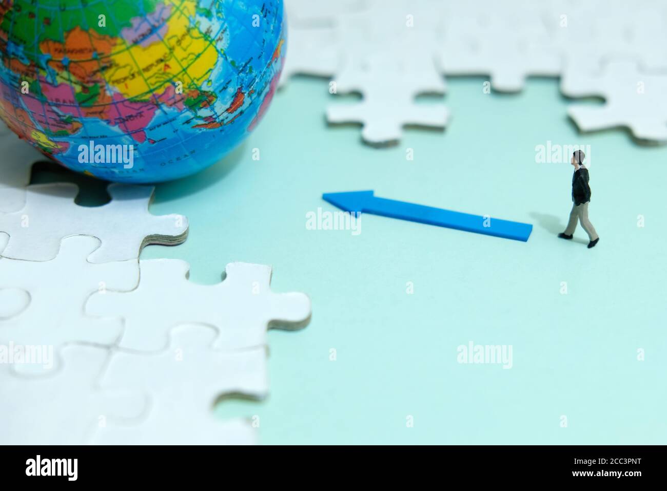Business-Strategie konzeptionelle Foto - Miniatur Geschäftsmann zu Fuß in den Globus In der Mitte des Puzzles Stockfoto