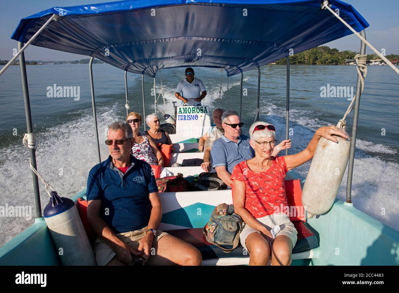 Westliche Touristen auf Exkursion im Touristenboot auf dem Dulce Fluss von der Stadt Rio Dulce zur Mündung in Livingston, Izabal Department, Guatemala Stockfoto