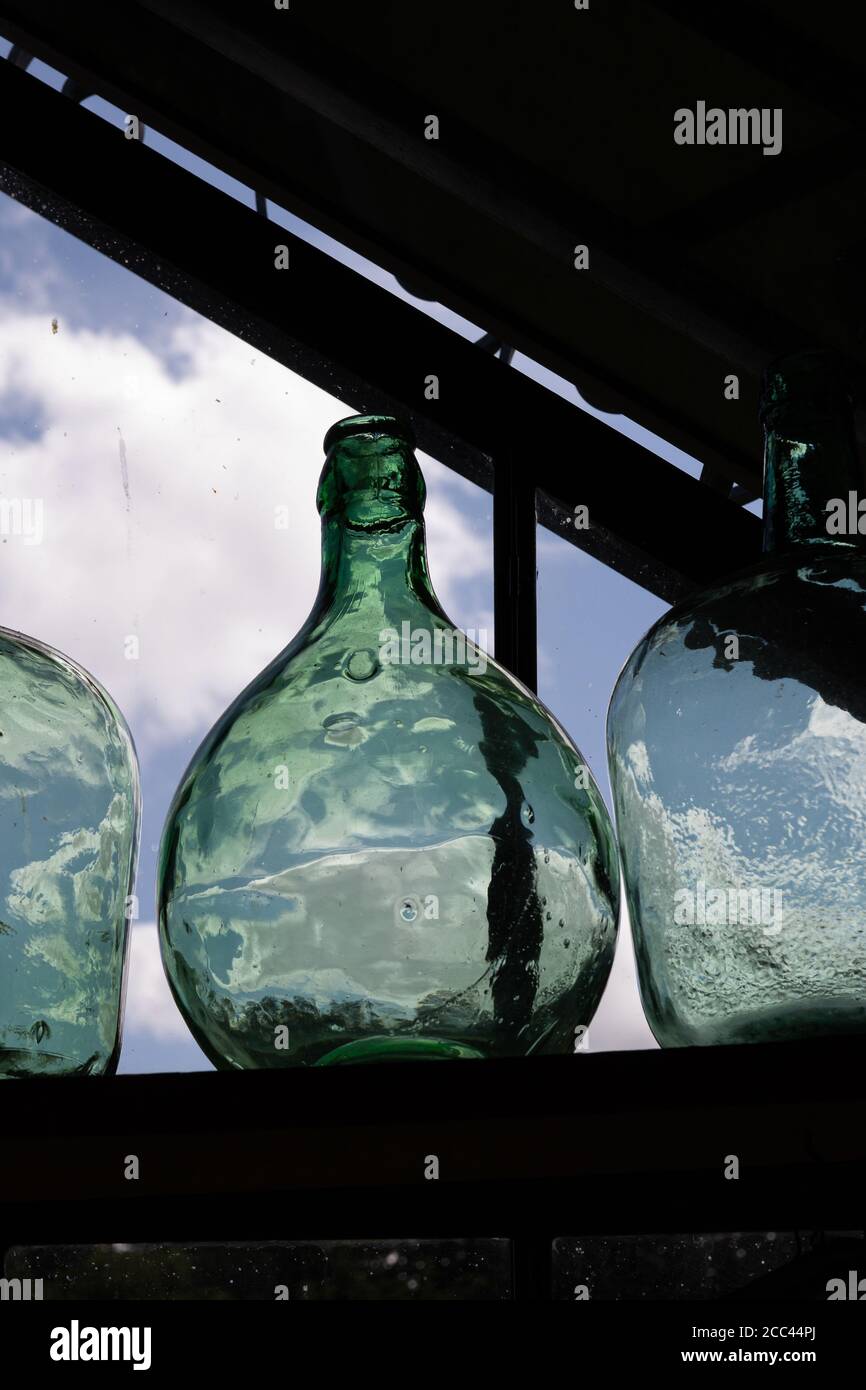 Grüne Flasche Dame Jeanne. Dekoratives Objekt auf der Veranda. Hochwertige Fotos Stockfoto