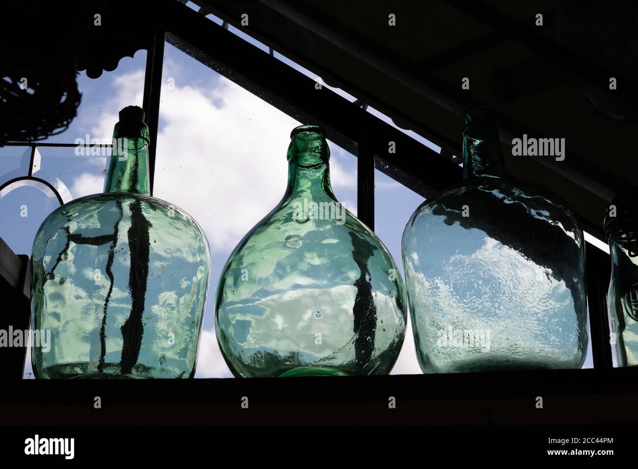 Grüne Flasche Dame Jeanne. Dekoratives Objekt auf der Veranda. Hochwertige Fotos Stockfoto