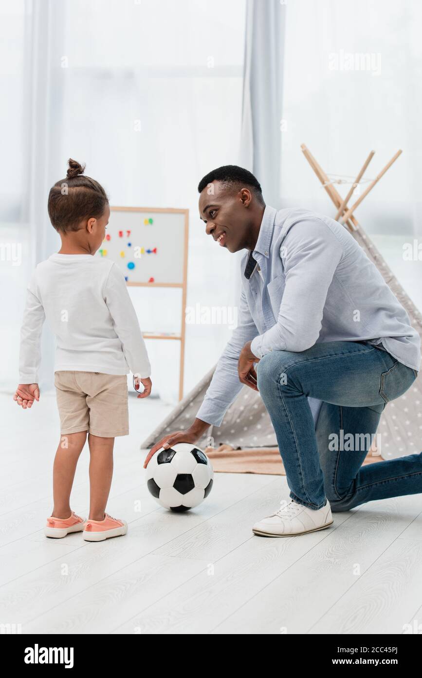 afroamerikanischer Vater berührt Fußball und schaut auf Kind Stockfoto