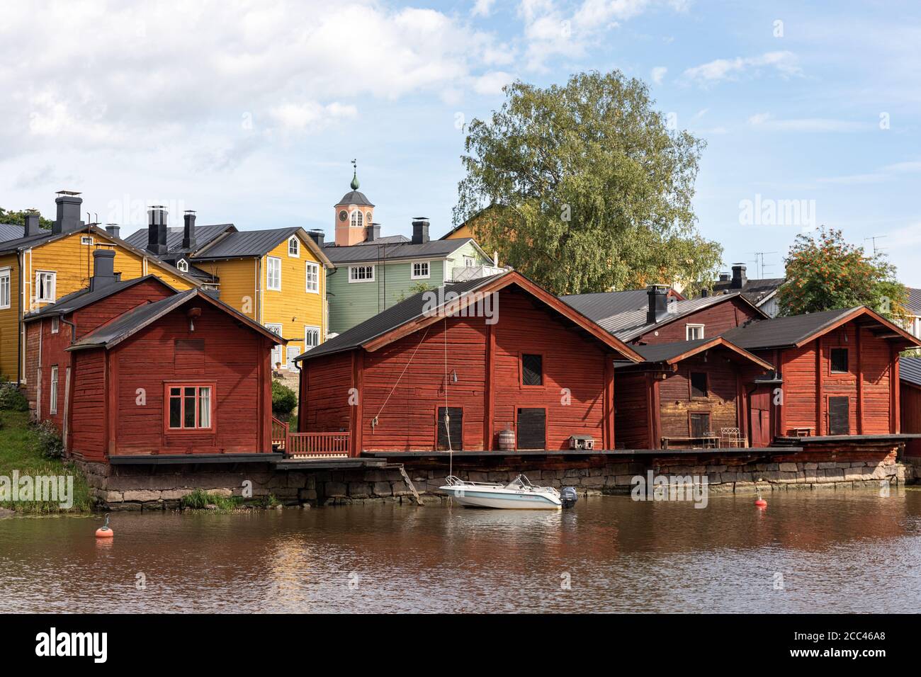 Alte rot-ockerfarbene Lagergebäude am Ufer von Porvoonjoki und Holzhäuser der Altstadt im Hintergrund in Porvoo, Finnland Stockfoto
