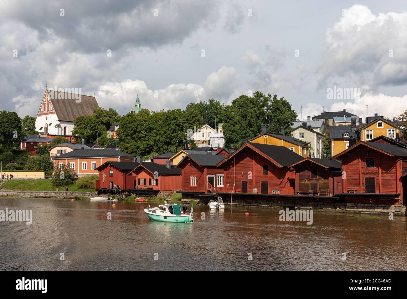 Fluss Porvoonjoki mit alten Holzlagerhäusern am Flussufer und mittelalterlicher Stein- und Backsteinkathedrale im Hintergrund in Porvoo, Finnland Stockfoto
