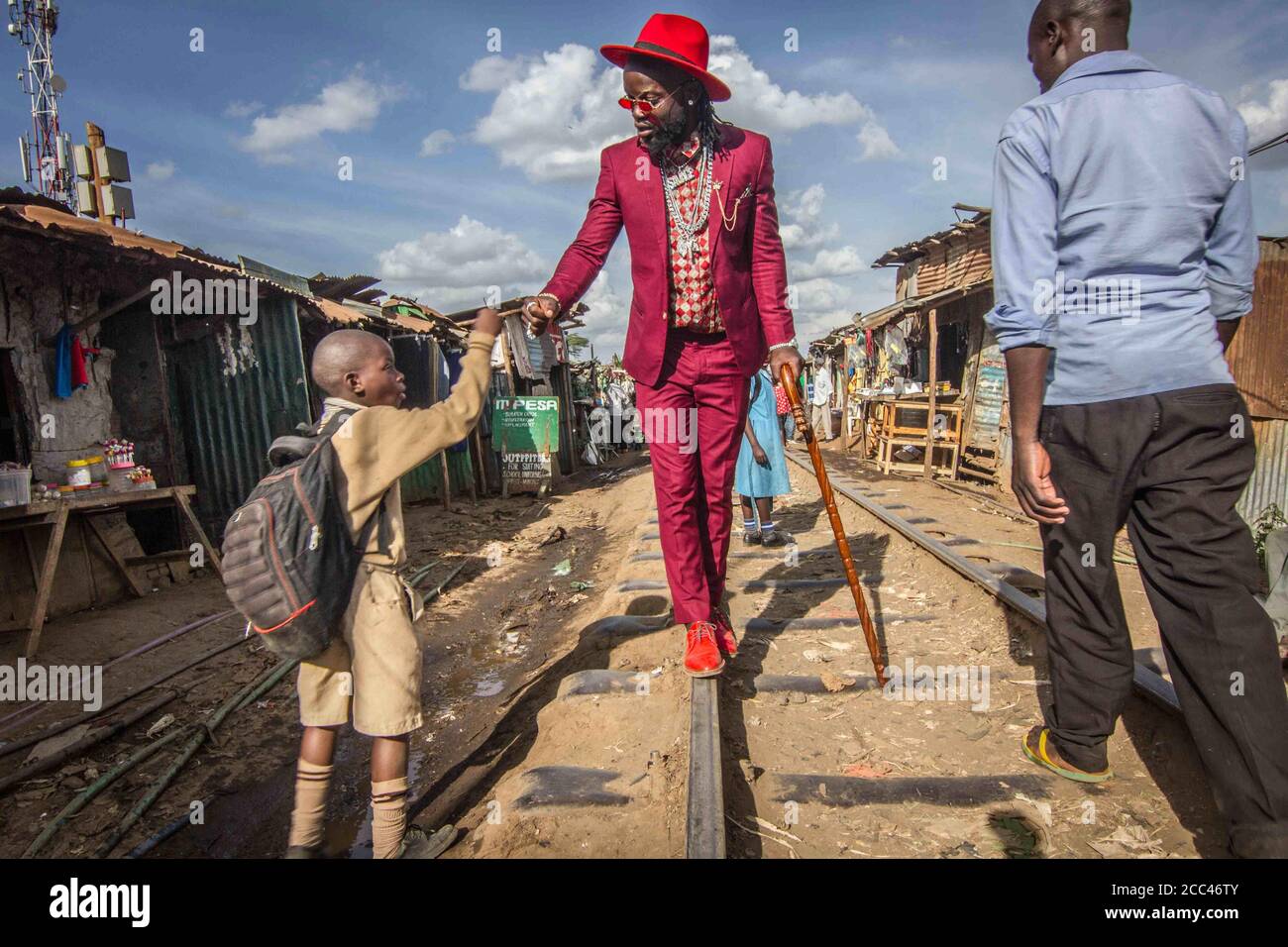 Nairobi, Kenia. Februar 2020. Baqterias geht in seinem eleganten Anzug an den Straßen der Slums von Kibera vorbei.die Jugendlichen in den Slums von Kibera tragen sorgfältig ausgewählte, passende, farblich abgestimmte Outfits. Für diese jungen Slummenschen ist Kunst eine individuelle, kreative Erfahrung und das Herzstück dieser Kunst ist Mode. Von der Malerei bis zu den Fotoshootings kann man erkennen, aus welcher Zeit das Motiv lebte. Glockenhosen und Afros in den ''˜80ern, Pumps und Schuhe mit dicken Sohlen in den ''˜70ern, Mini-Röcke und bunte Tops in den ''˜60s gibt es viel zu lesen aus einem Fotoshooting. (Bild: © Wilson Odhiambo/SO Stockfoto