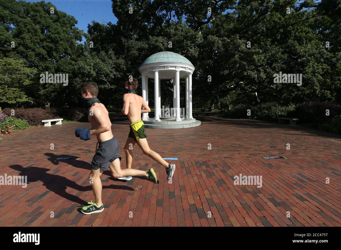 Chapel Hill, North Carolina, USA. August 2020. Zwei Läufer joggen am berühmten Alten Brunnen auf dem Campus des UNC-Chapel Hill vorbei. Die Schule wird ab Mittwoch alle Grundschulklassen online verlegen, nachdem 130 weitere Schüler positiv auf das Coronavirus getestet wurden. Es gab Berichte von vier COVID-19-Clustern über drei Tage in Schlafsälen, Wohnungen und einem Brüderungshaus. Quelle: Bob Karp/ZUMA Wire/Alamy Live News Stockfoto