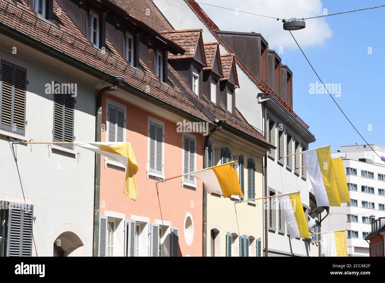 Flagge der Vatikanstadt wehend aus den Fenstern der traditionellen alten Häuser in der Nähe des Freiburger Münster in der Innenstadt von Freiburg im Breisgau, Deutschland. Stockfoto