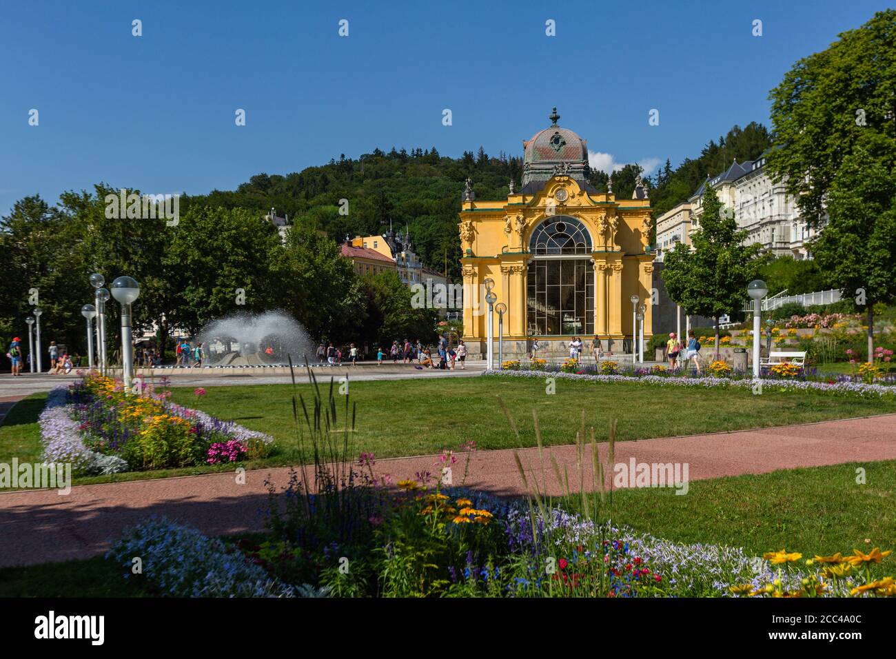 Marianske Lazne / Tschechien - August 11 2020: Blick auf die Maxim Gorki Kolonnade mit gelbem Gebäude, Wasserbrunnen, grüner Wiese und Blumen. Stockfoto