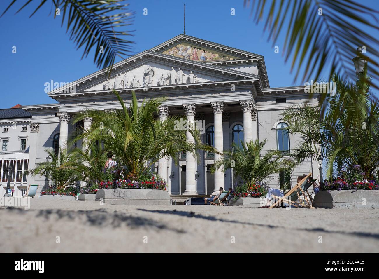 München, Deutschland - 9. August 2020: Ein temporärer Palmenstrand wurde vor das Nationaltheater in München gebracht, um "Sommer in der Stadt" zu feiern Stockfoto