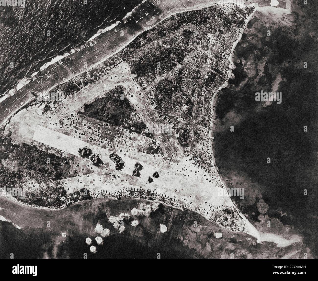 Explosionen großer Flugzeugbomben auf der japanischen Landebahn auf dem Woleai Atoll in Mikronesien. Spuren früherer Bombenanschläge sind sichtbar. Diese Mission war Auto Stockfoto