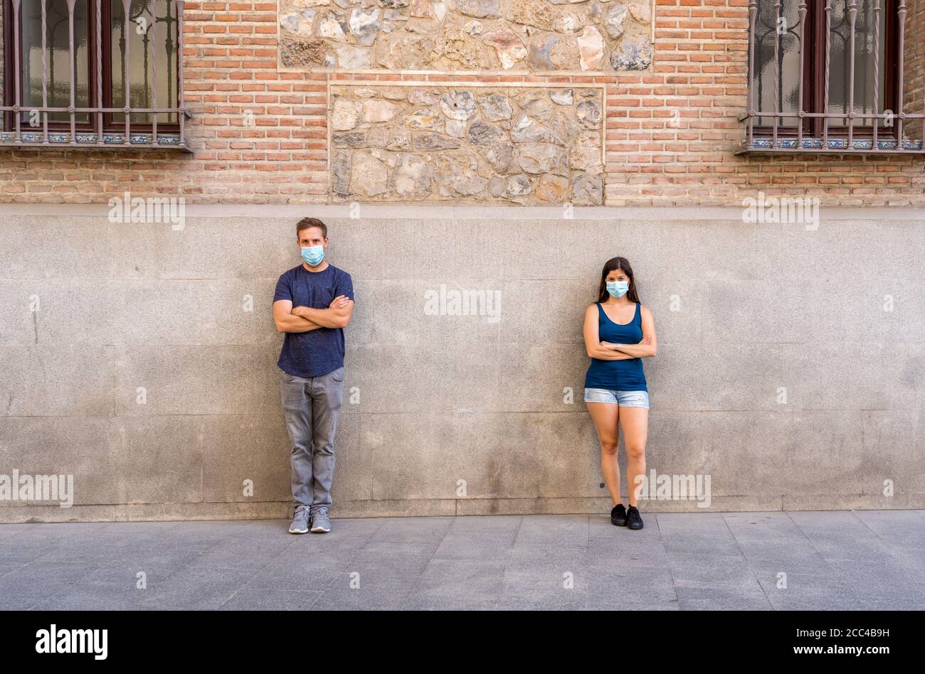 Mann und Frau tragen schützende Gesichtsmasken, die 2 m voneinander entfernt stehen und soziale Distanz halten, um die Ausbreitung des Coronavirus zu vermeiden. Konzeptionelle imag Stockfoto