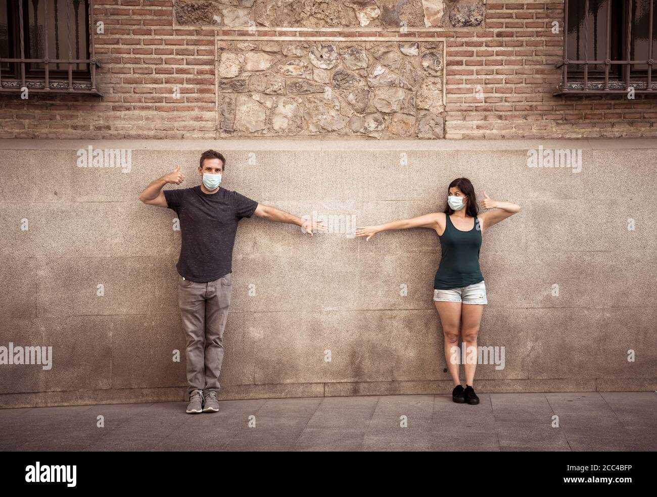 Mann und Frau tragen schützende Gesichtsmasken, die 2 m voneinander entfernt stehen und soziale Distanz halten, um die Ausbreitung des Coronavirus zu vermeiden. Konzeptionelle imag Stockfoto
