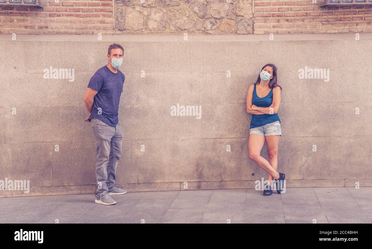 Mann und Frau tragen schützende Gesichtsmasken, die 2 m voneinander entfernt stehen und soziale Distanz halten, um die Ausbreitung des Coronavirus zu vermeiden. Konzeptionelle imag Stockfoto