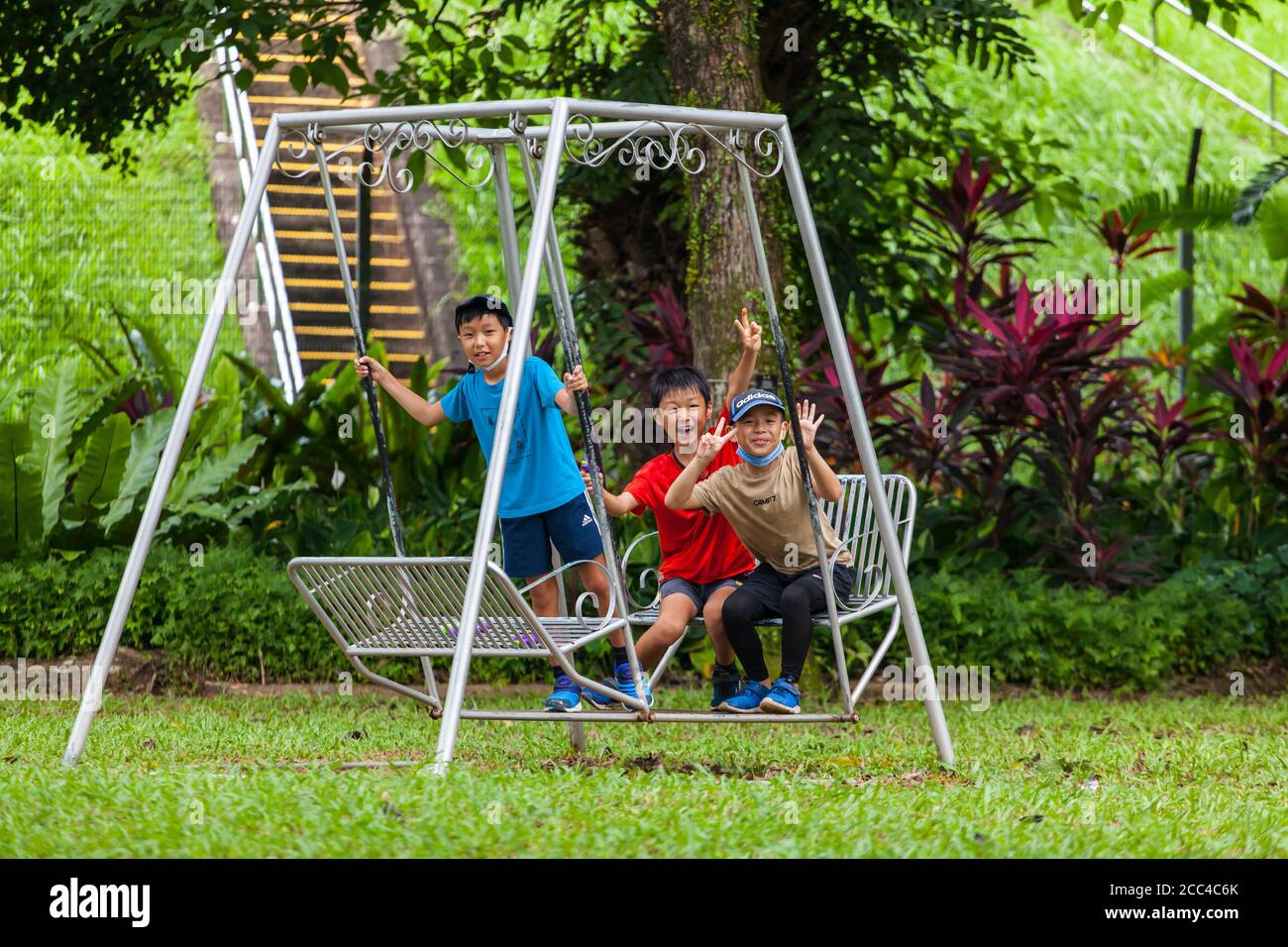 Japanische Kinder machen süße Posen und fröhliches Gesicht auf der Schaukel. Die Freundschaft der Kinder ist voller Energie, hoher Geist, Glück. Fort Canning, Singapur. Stockfoto