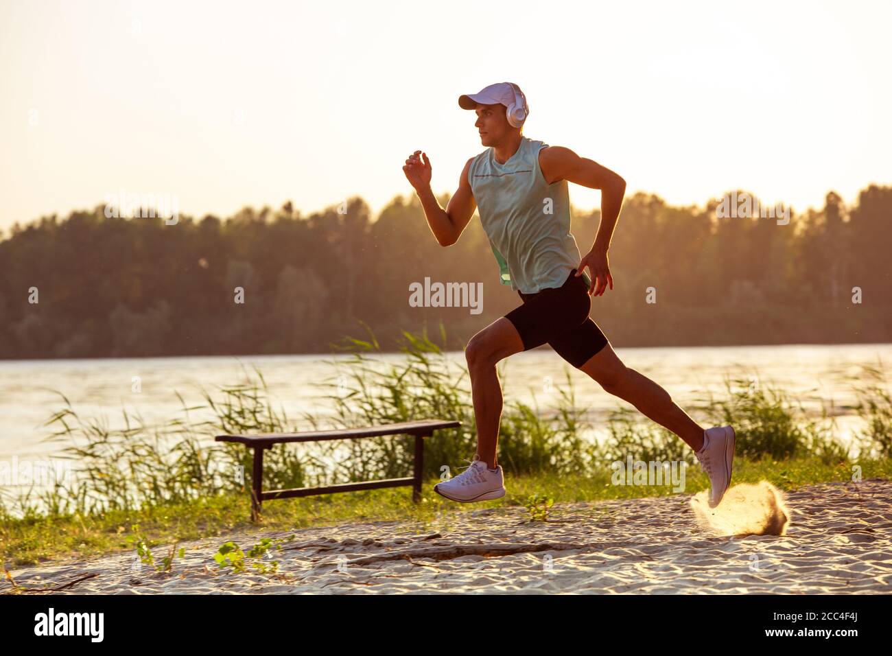 Laufen, Joggen. Ein junger Sportler, der draußen am Flussufer trainieren und Musik hören kann. Konzept für einen gesunden Lebensstil, Wellness, Sport, Aktivität, Gewichtsverlust. Inspiriert von der Natur, Sommerzeit. Stockfoto