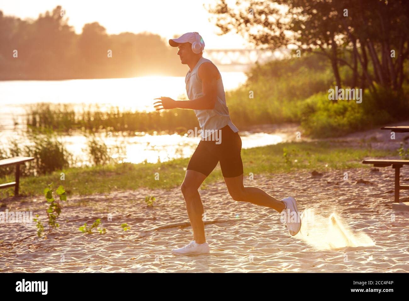 Laufen, Joggen. Ein junger Sportler, der draußen am Flussufer trainieren und Musik hören kann. Konzept für einen gesunden Lebensstil, Wellness, Sport, Aktivität, Gewichtsverlust. Inspiriert von der Natur, Sommerzeit. Stockfoto