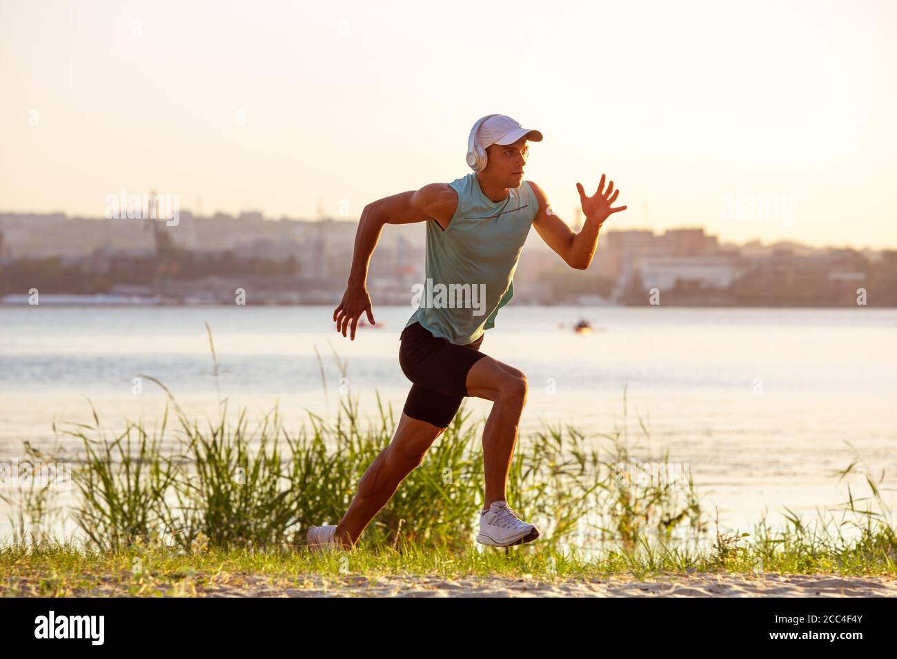Laufen, Joggen. Ein junger Sportler, der draußen am Flussufer trainieren und Musik hören kann. Konzept für einen gesunden Lebensstil, Wellness, Sport, Aktivität, Gewichtsverlust. Inspiriert von der Natur, Sommerzeit. Stockfoto