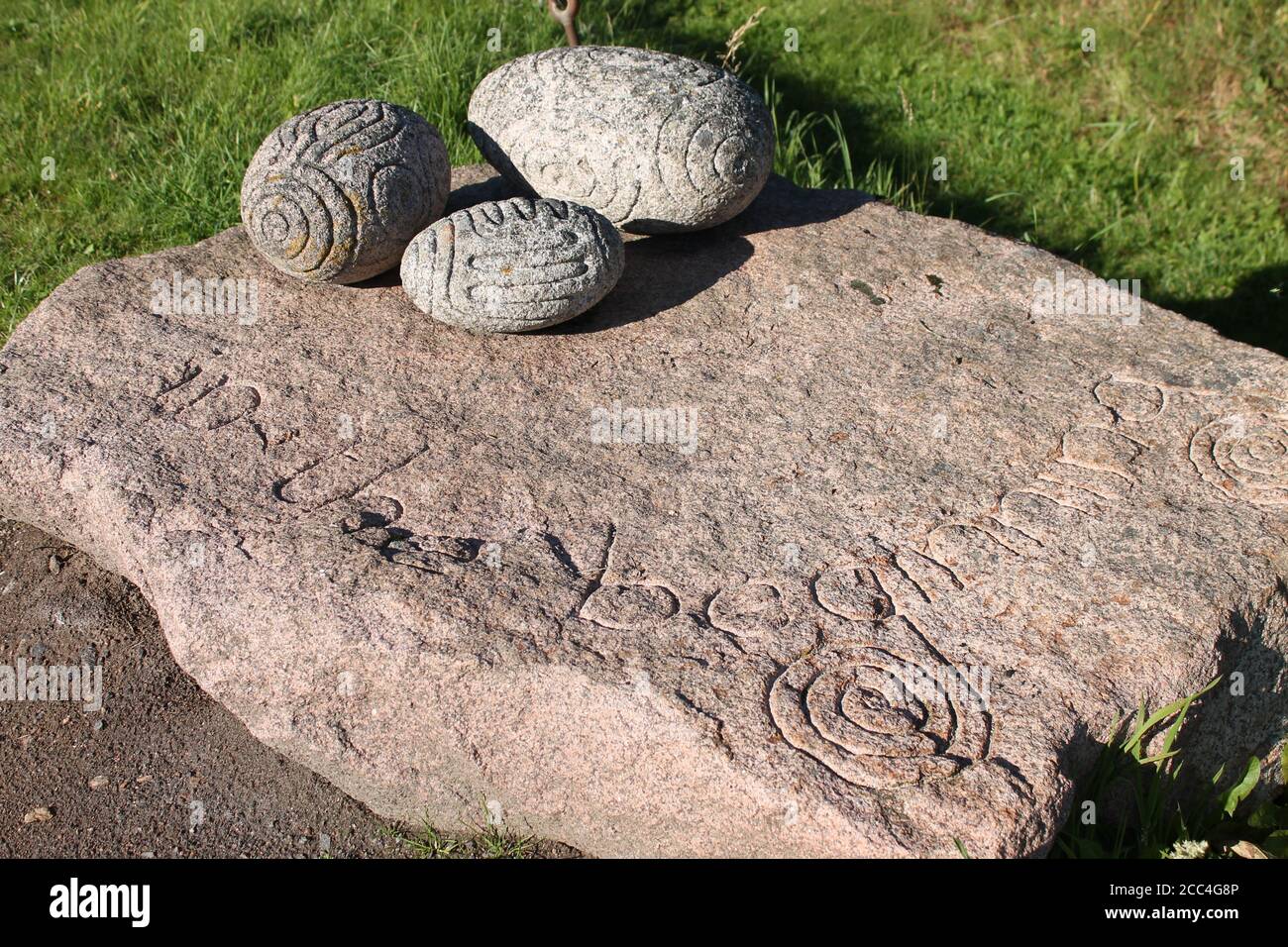 Geschnitzte längliche Steine, ähnliches Design wie Towie-Kugeln auf einer Steinschnitzerei. Kunst im megalithischen Stil Stockfoto