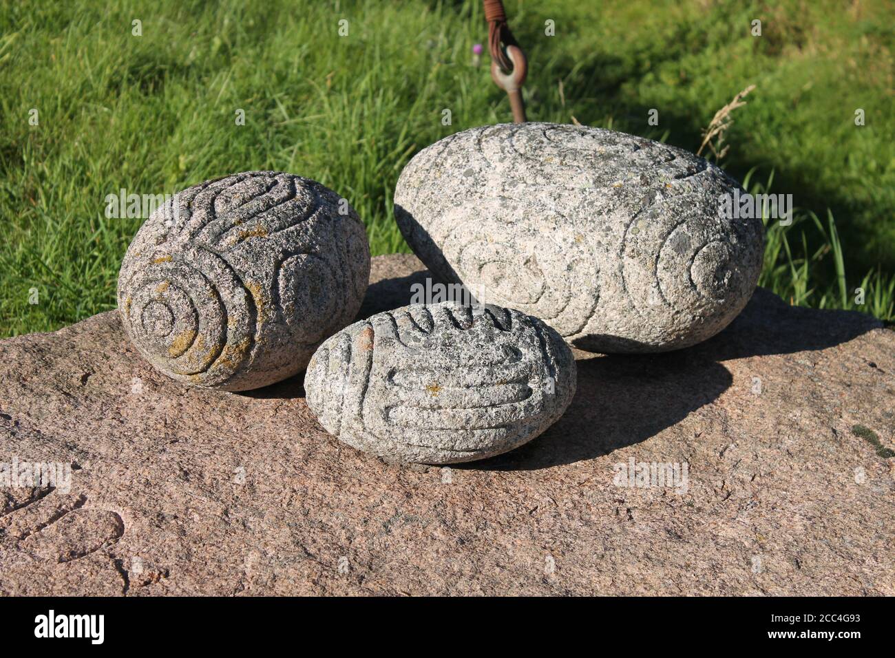 Drei geschnitzte längliche Steine, ähnlich wie Towie Kugeln. Kunst im megalithischen Stil Stockfoto