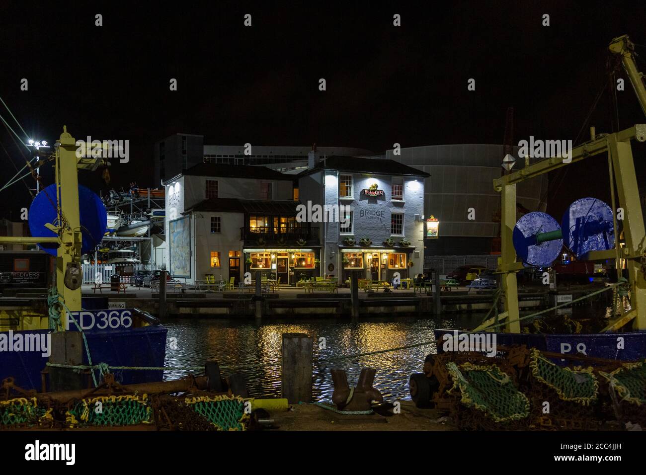 Der Bridge Tavern Pub in Old Portsmouth ist beleuchtet Nacht mit Fischerbooten im Vordergrund Stockfoto