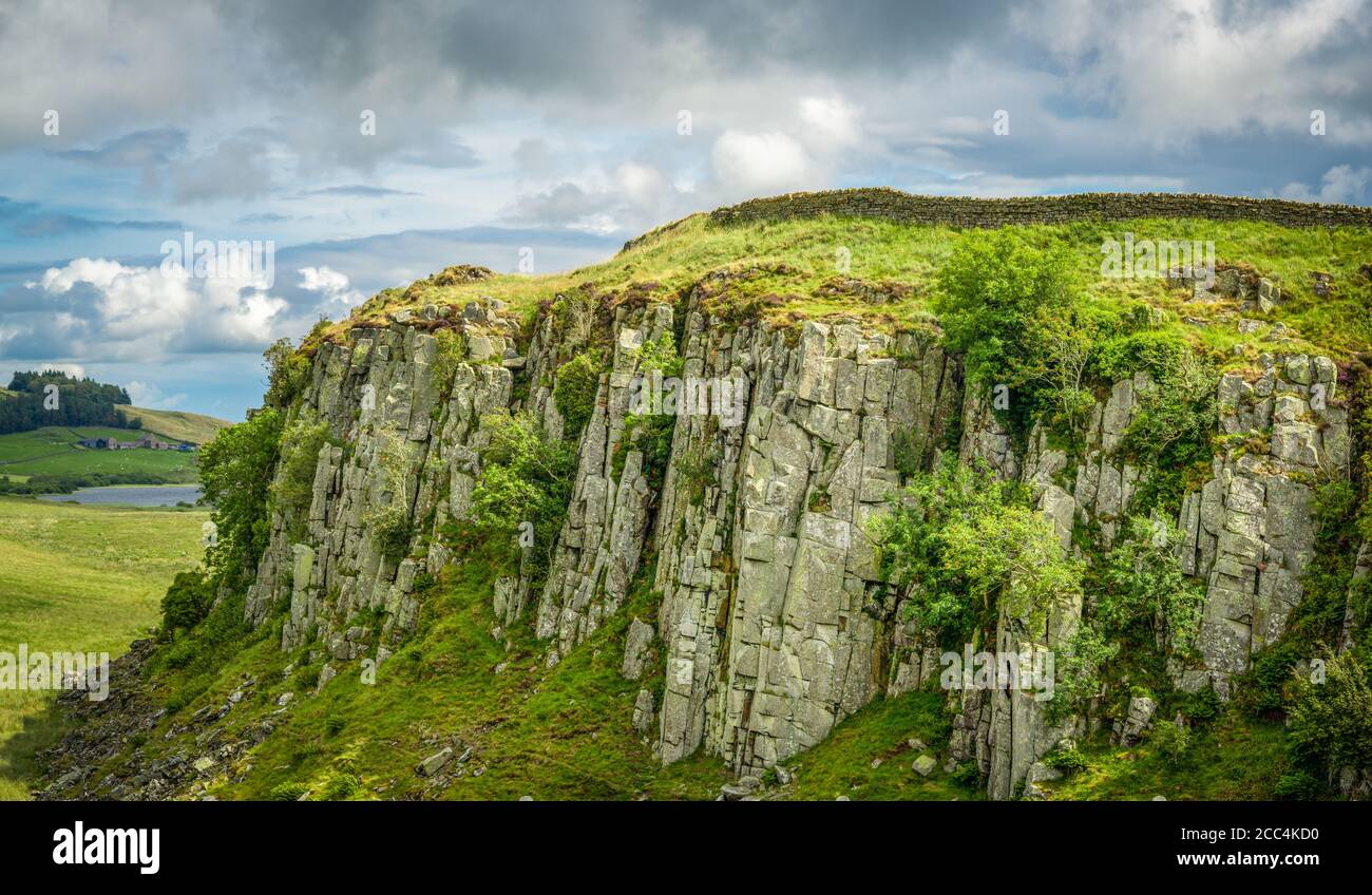 Abschnitt der Hadrianmauer auf der Oberseite des Großen Whins Sill Escarpment in Northumberland England mit Crag Lough in der Hintergrund Stockfoto