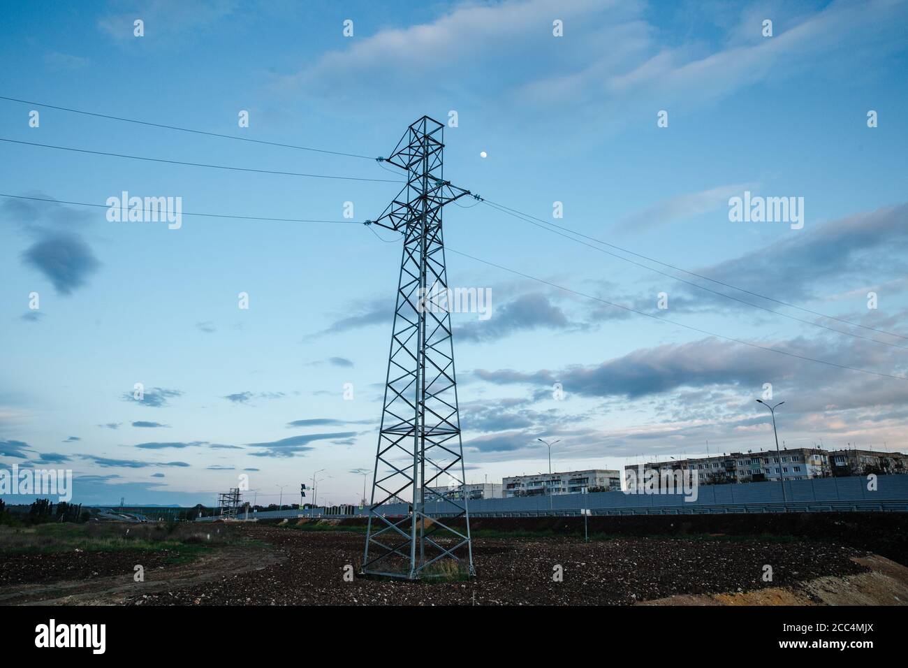 Hochspannungsturm aus Metall auf einem Sonnenuntergangshintergrund. Stockfoto