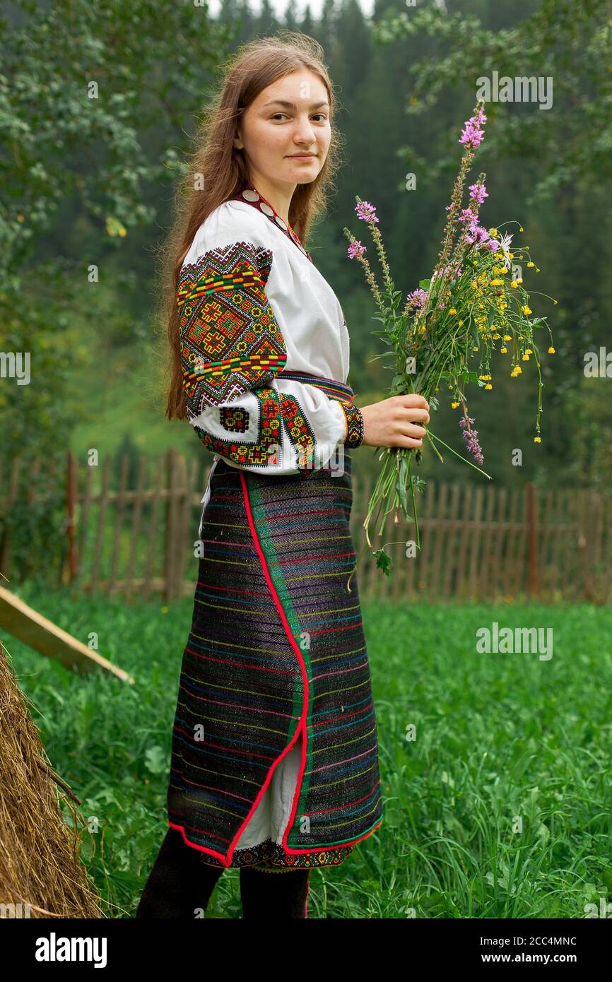 Mädchen mit lockeren Haaren mit einem Blumenstrauß steht Bei einem Heuhaufen Stockfoto