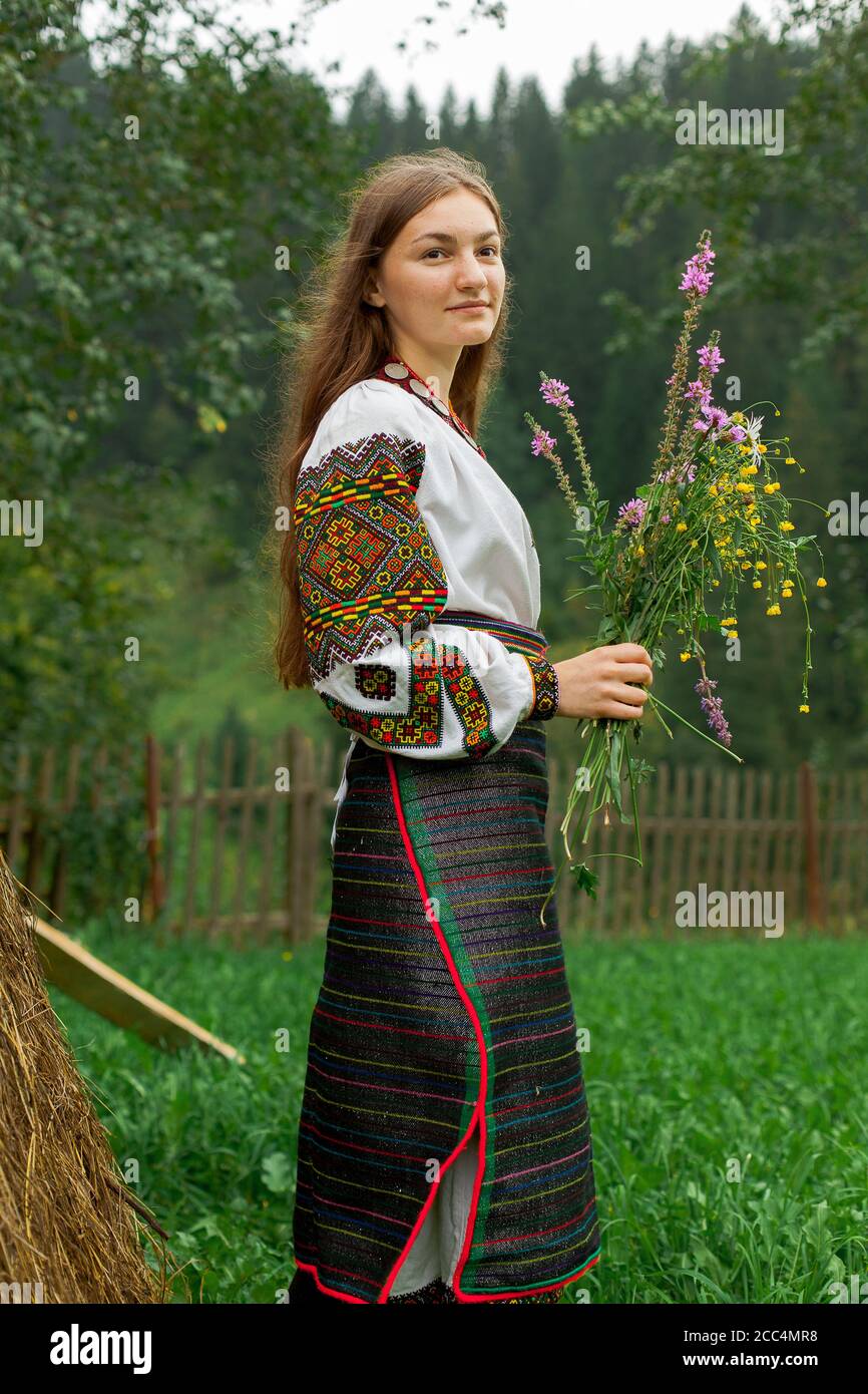 Mädchen mit lockeren Haaren mit einem Blumenstrauß steht Bei einem Heuhaufen Stockfoto