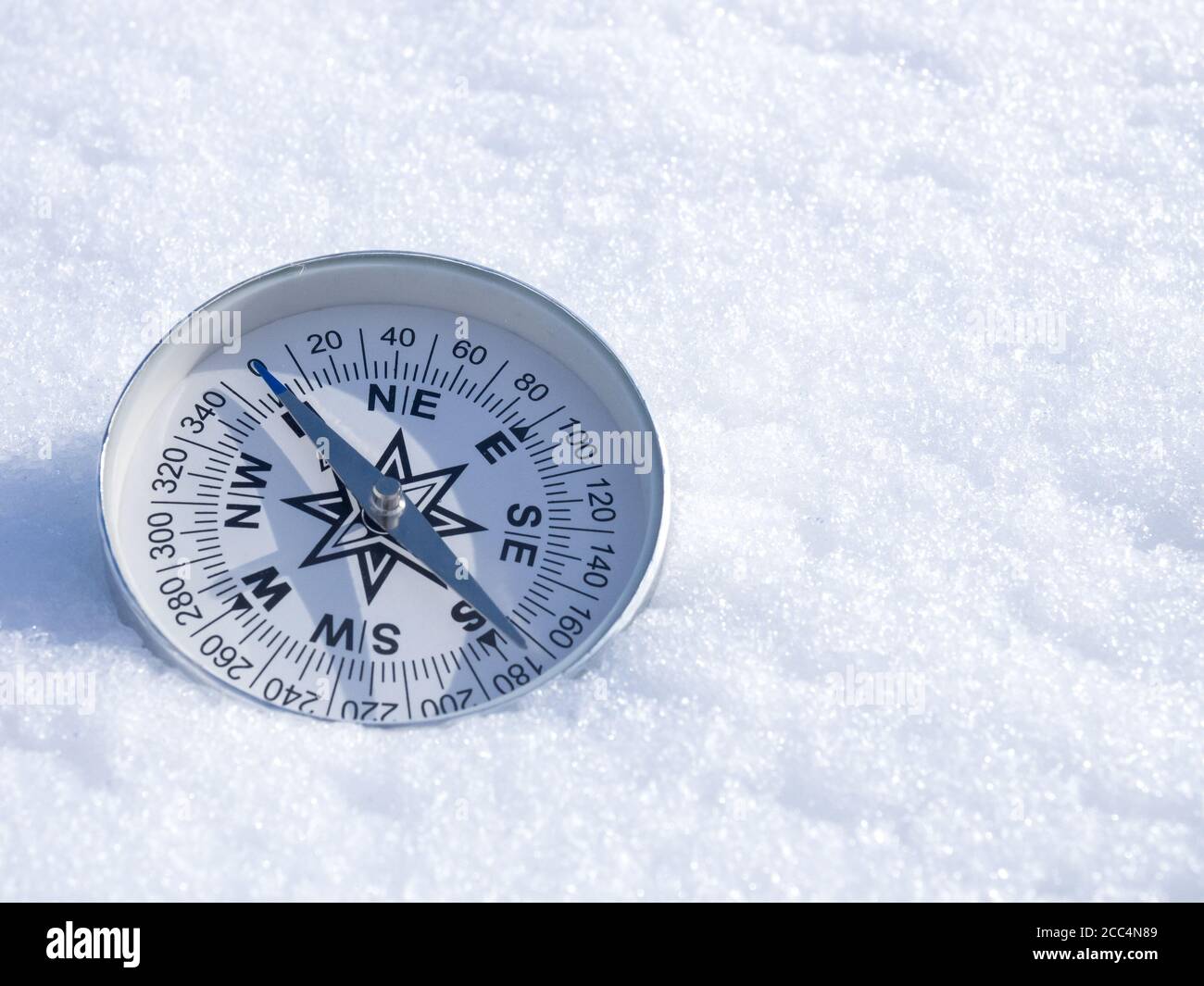 Rund moderner Kompass auf dem weißen Schnee, Platz für Text. Konzept für Reisen und aktiven Lebensstil Stockfoto