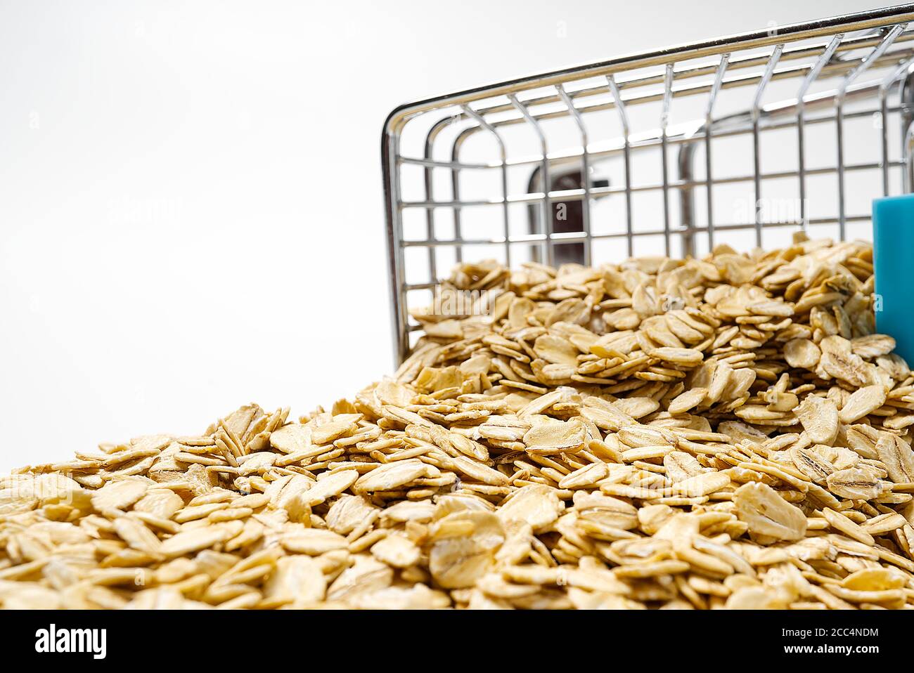 Warenkorb voll mit Haferflocken. Supermarkt-Trolley mit goldenen Haferflocken auf weißem Hintergrund. Gesunde Ernährung. Stockfoto