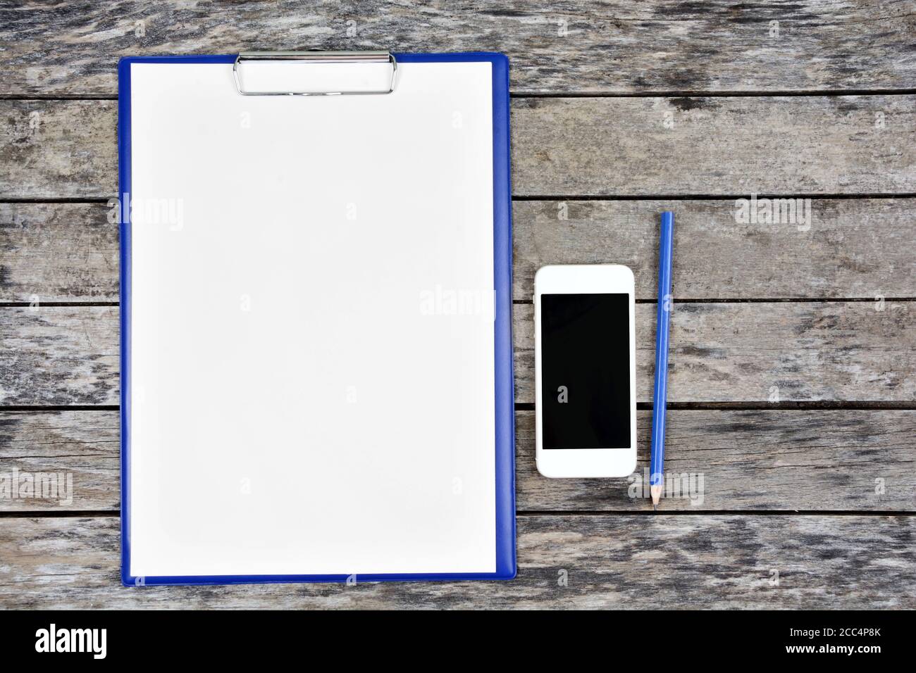 Zwischenablage mit leerem weißem Papier mit Bleistift und Telefon an Schreibtisch Stockfoto