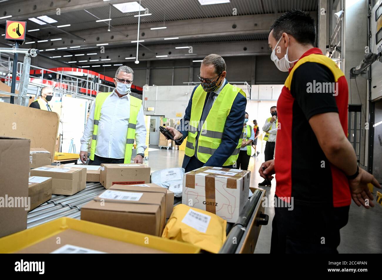 Berlin, Deutschland. August 2020. Der Regierende Bürgermeister von Berlin, Michael Müller (SPD, M), lässt den Paketdienstleister Maik Berkholz (r) die Arbeitsabläufe an der DHL-Zustellbasis in Marzahn erläutern. Kredit: Britta Pedersen/dpa-Zentralbild/dpa - ACHTUNG: Barcodes auf den Paketen wurden aus rechtlichen Gründen pixeliert/dpa/Alamy Live News Stockfoto