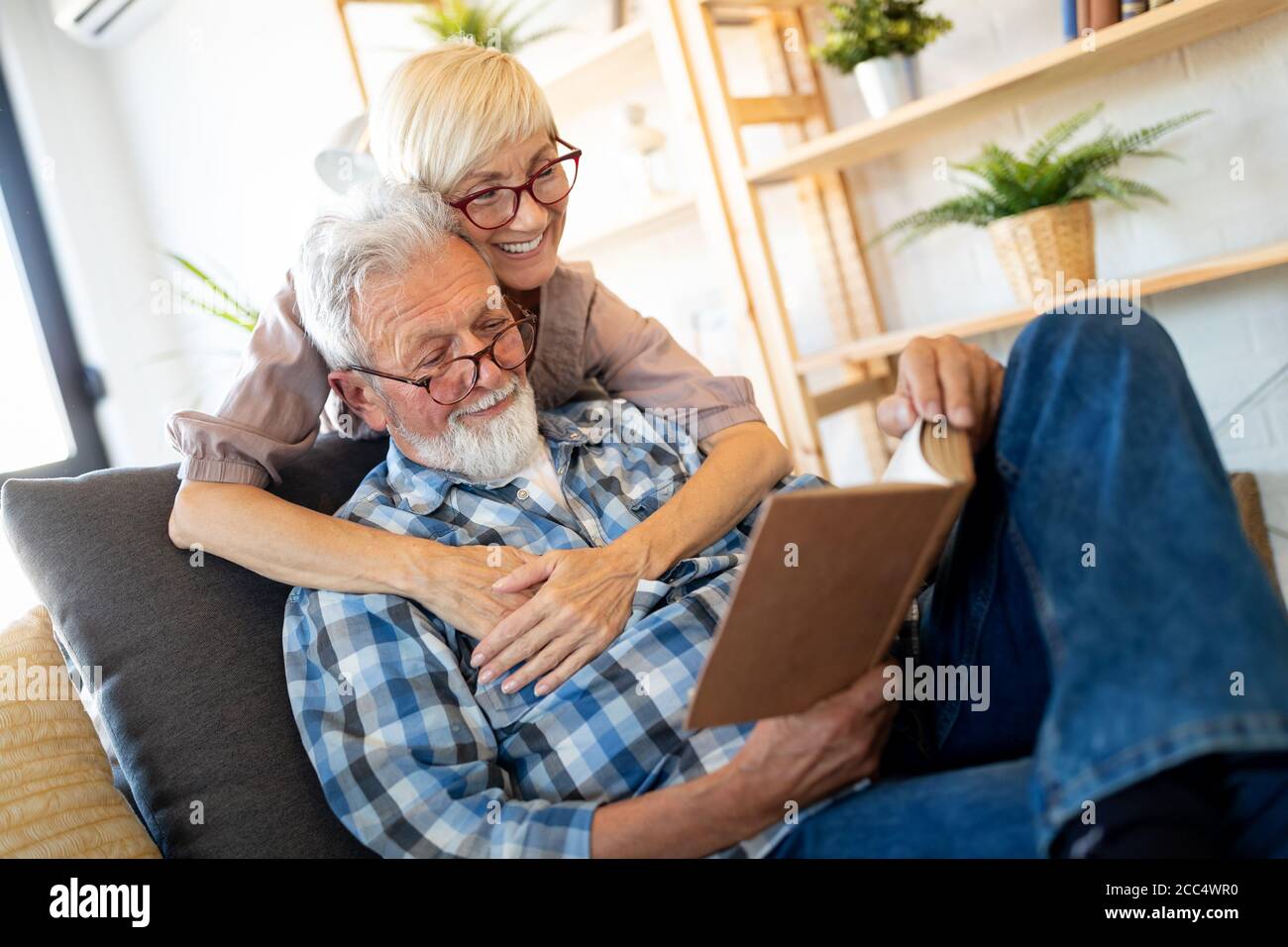 Schöne alte Paar ist ein Buch zu lesen und zu Hause lächeln Stockfoto