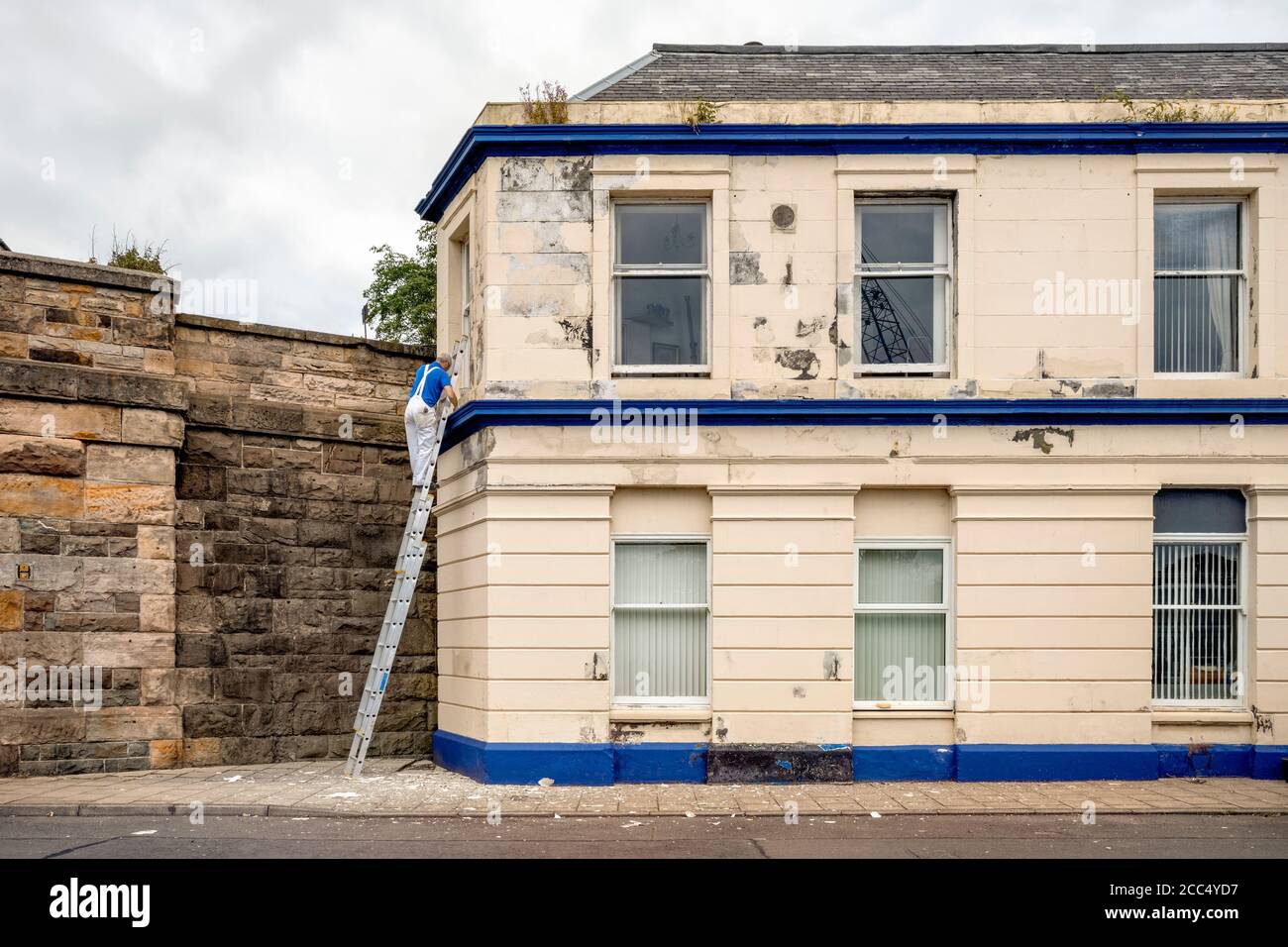 Maler auf einer Leiter Malerei ein Haus. Stockfoto