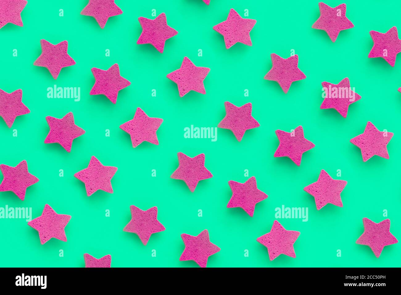 Rosa Sterne auf grünem Hintergrund, Platz für Text. Rosa Cookies. Speicherplatz kopieren. Modell Stockfoto