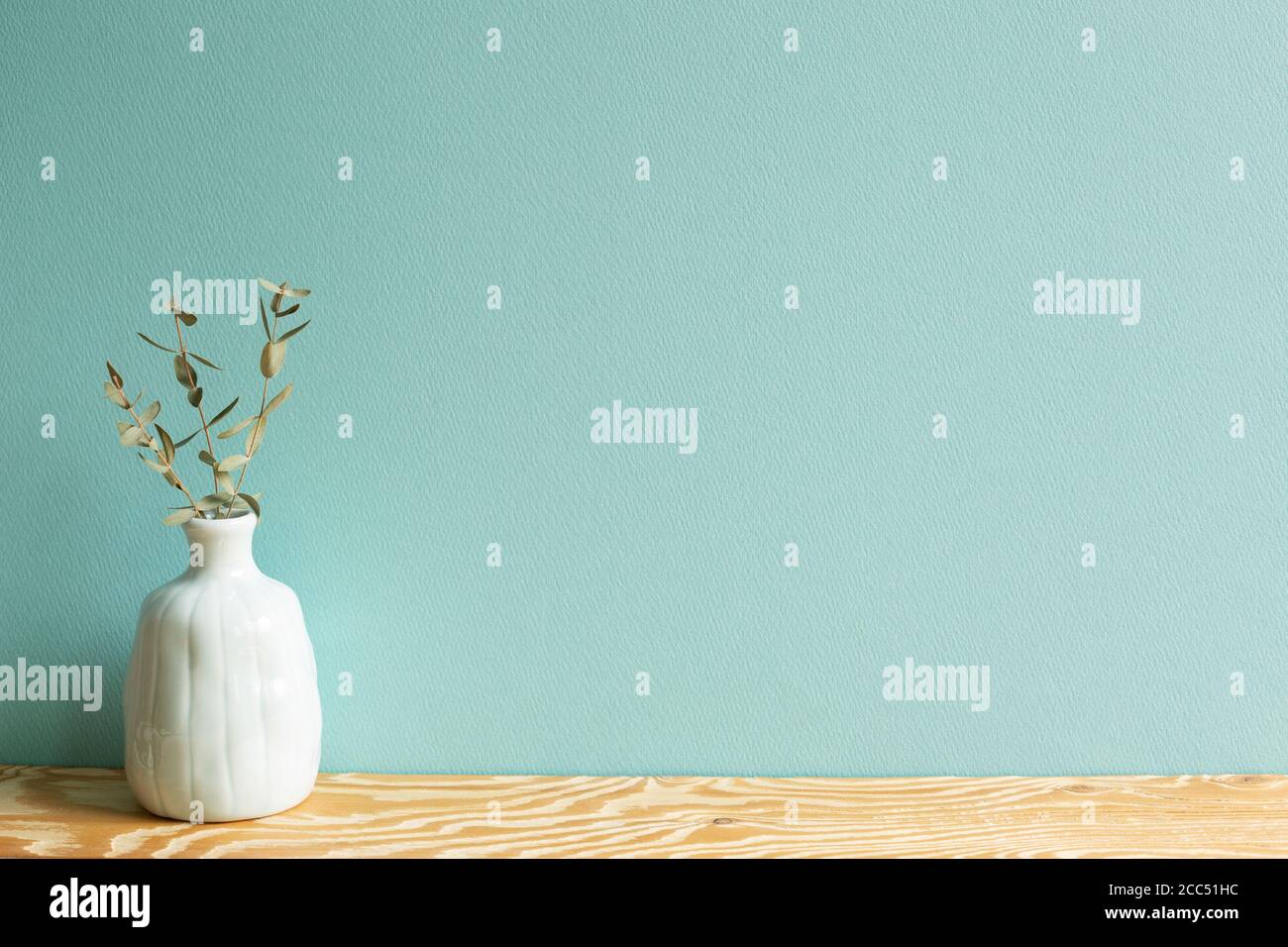Vase aus Eukalyptusblättern auf Holztisch mit grünem Hintergrund Stockfoto