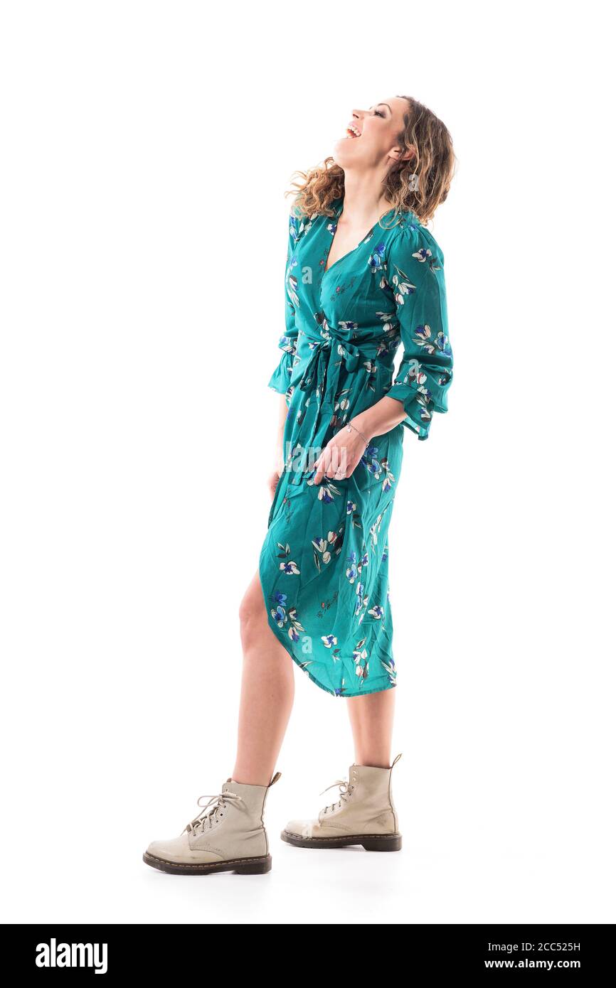 Seitenansicht der entspannten unbeschwerten Frau lachen und Spaß in grünen Kleid. Ganzkörperlänge isoliert auf weißem Hintergrund. Stockfoto