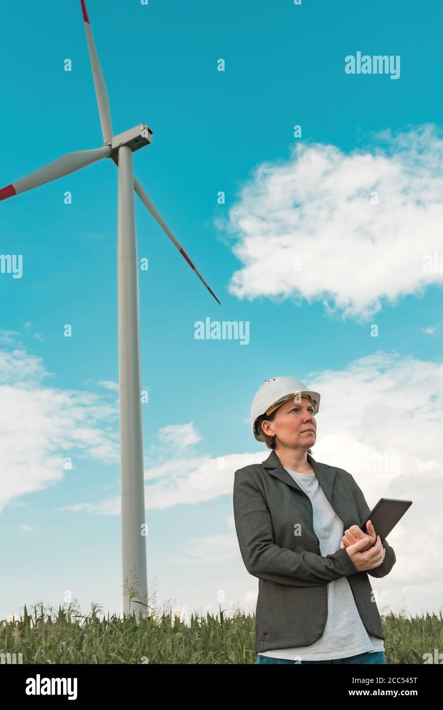 Ingenieurin mit Tablet-Computer auf einem modernen Windturbinenpark während der Wartungsplanung Stockfoto