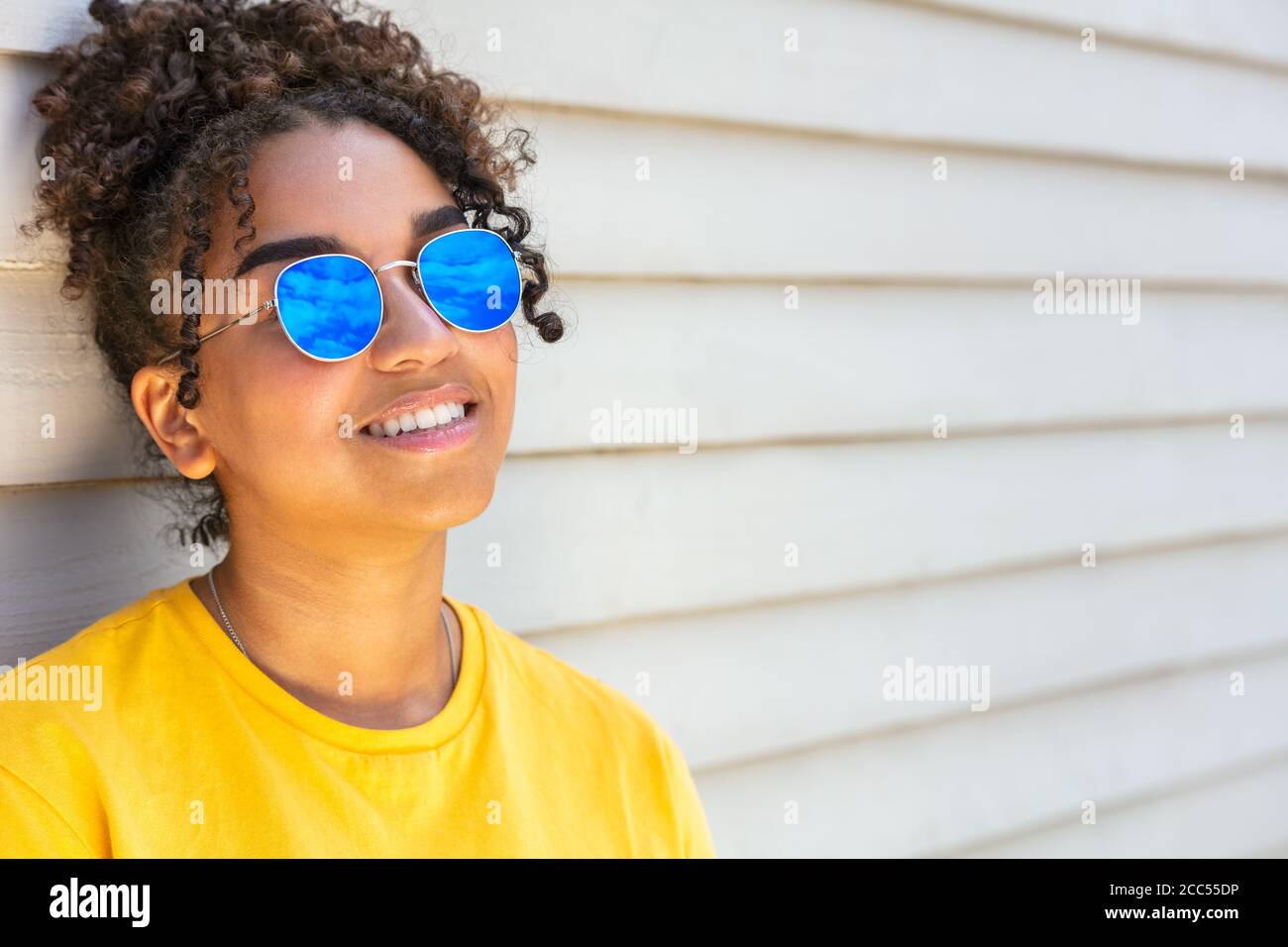 Mädchen Teenager Teenager gemischt Rasse biracial afroamerikanischen weiblich jung Frau trägt blaue Sonnenbrille lächelt mit perfekten Zähnen im Urlaub Im Sommer so Stockfoto