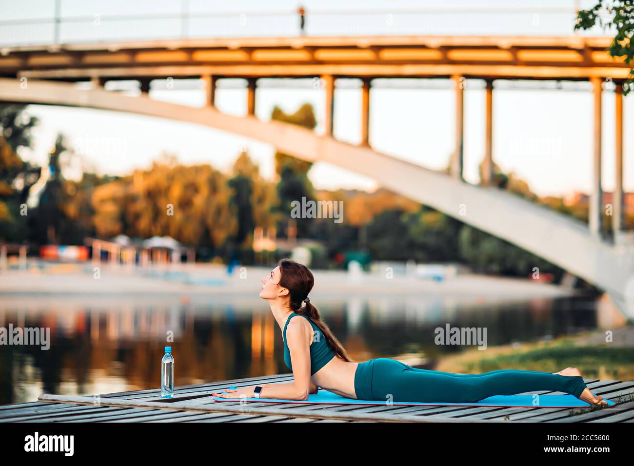 Sportlerin macht Yoga auf hölzerner Plattform Stockfoto