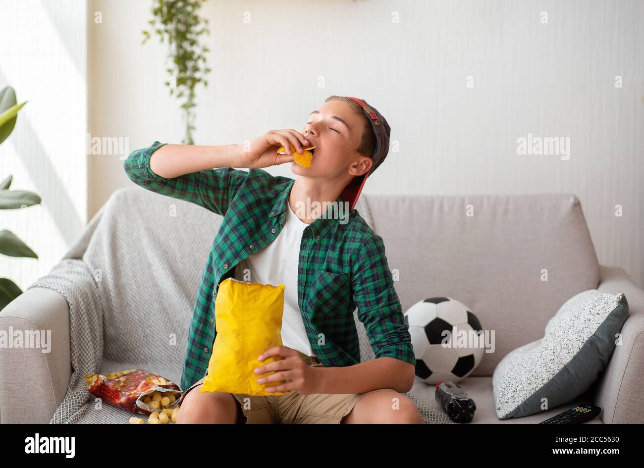 Teen Kerl genießen Chips beim beobachten Fußballspiel Stockfoto
