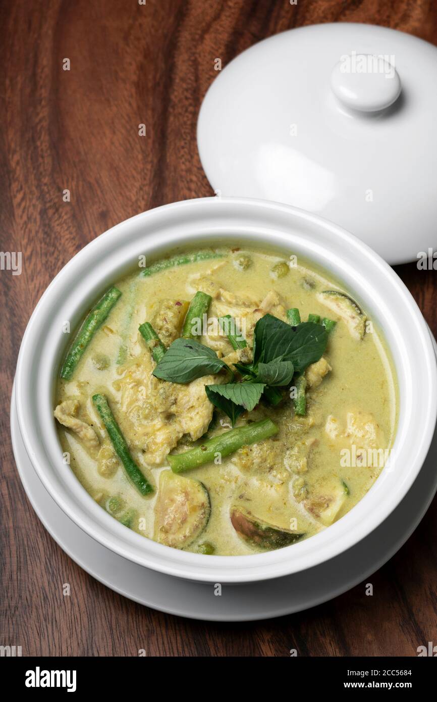 thailändisches grünes Curry mit Huhn und Gemüse auf Holztisch Stockfoto